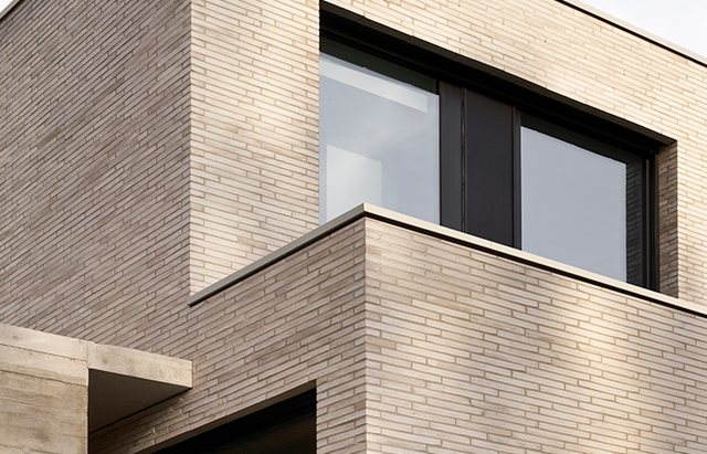 Corner of a building in light facing brick with a visible joint pattern