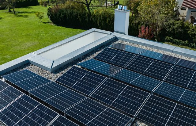 Photovoltaic modules on a flat roof, with garden and trees behind
